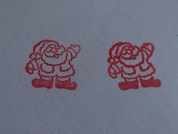 Zwei roter Stempel von einem Weihnachtsmann auf einem weißen Blatt Papier.