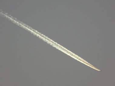 Ein steil absteigendes Flugzeug mit einem hellen Schweif.