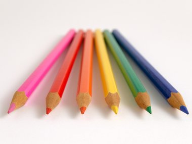 Sechs farbige Buntstifte liegen nebeneinander.