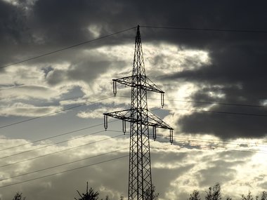 Ein Strommasten vor einem Wolkenhimmel.